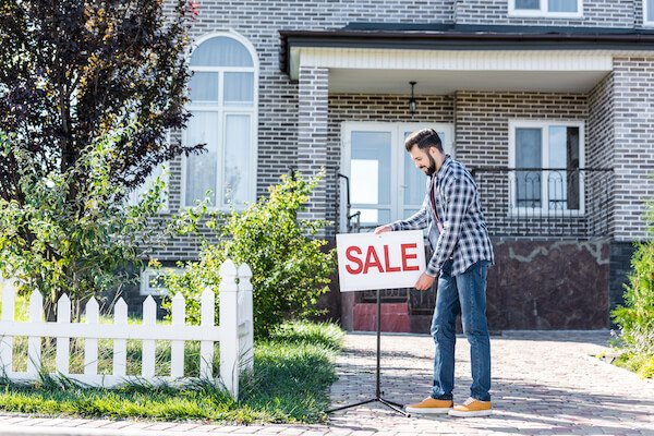 a man putting a for sale sign for his house so he need not to worry about taking over payments