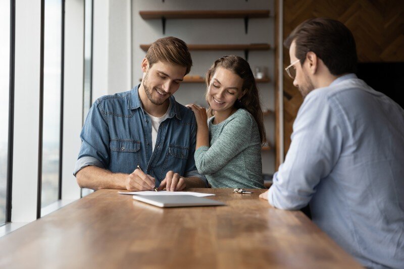 A couple signing some documents after having purchased their home.