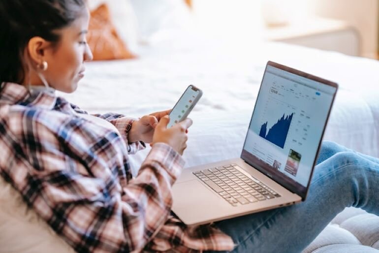 A woman with a laptop and a smartphone.