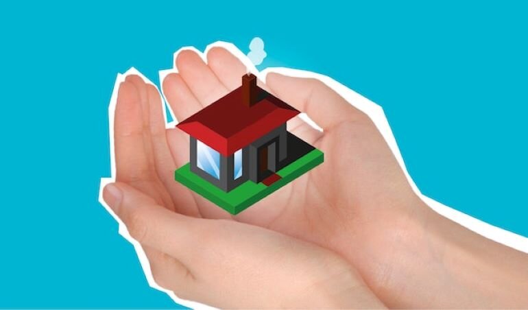 A person is holding a house model in his hands.