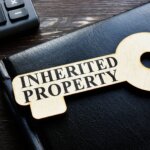 Wooden key on desk top imprinted with I inherited a house