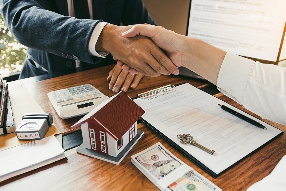 Home sales agents and buyers work on signing new homes and shaking hands.