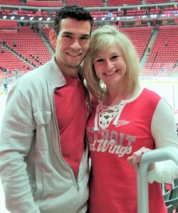 Founder of Amaze Properties LLC and josephbuyshomes.com, Joe Mazur and wife standing in hockey arena in Detroit MI