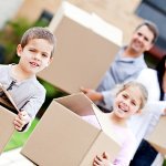 Family moving home and carrying cardboard boxes