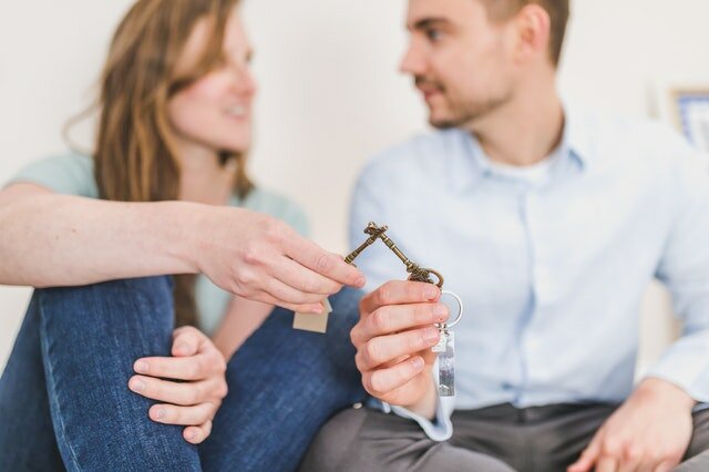 A woman and a man sitting next to each other and holding keys for a house in Louisburg NC.