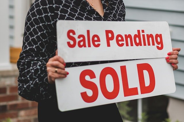 a woman holding a sale sign.