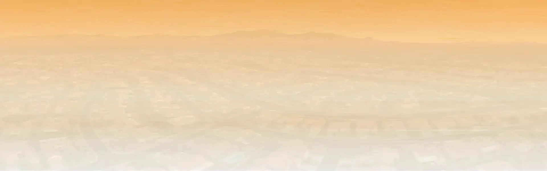 Phoenix skyline and housing rooftops at sunset with desert mountains in the background.