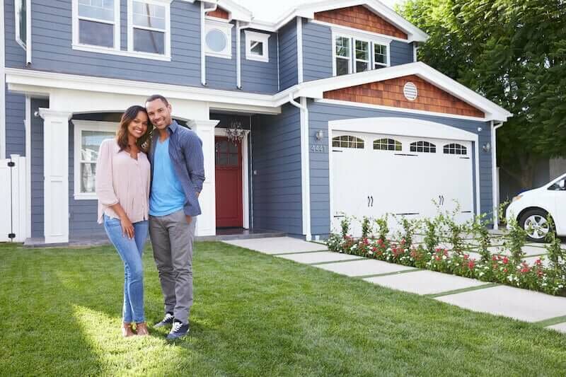 A young couple of homeowners standing in front of their house in Milwaukee