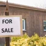House with for sale sign in front yard
