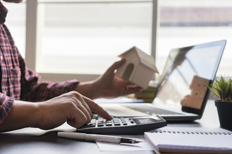 A man is calculating Nebraska Property Tax Exemptions by doing some calculations on a laptop, and a calculator.