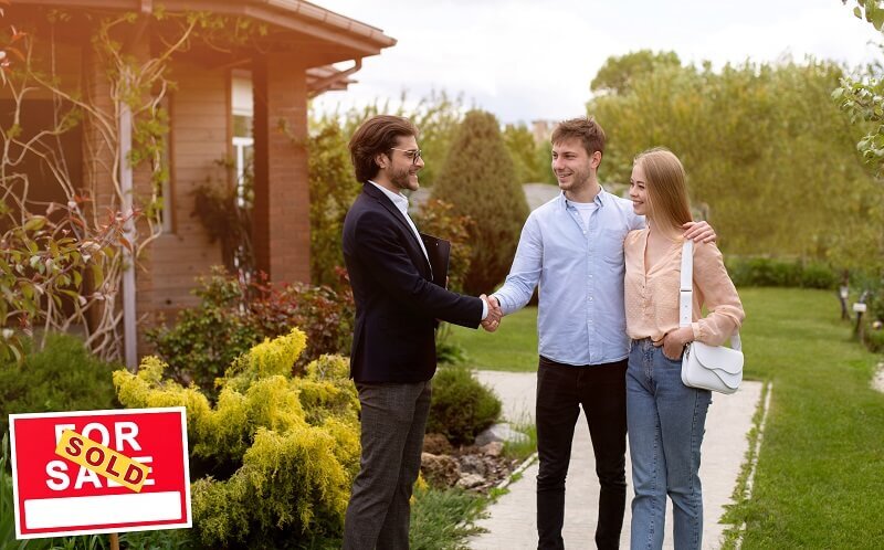 Two young homeowners shake hands with a real estate investor after selling a house before paying off mortgage