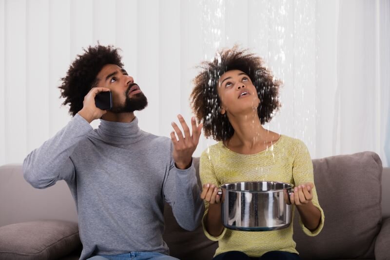 A couple evaluates water damage made to the house while calling a plumber. 