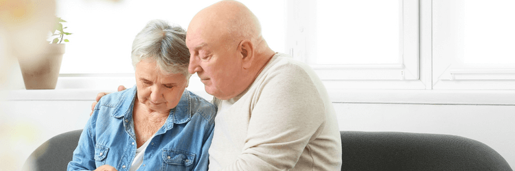 Two elderly homeowners reading about the costs of a stagnant listing