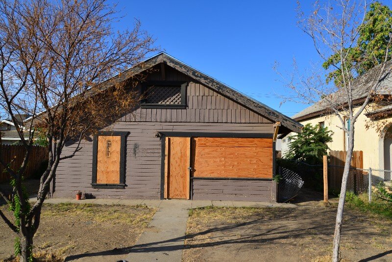 A house that has been condemned has its windows shut with plywood. 