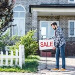 man putting a sale sign - house for sale fast