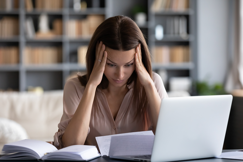 A young woman pressing her head and worried about not knowing Idaho's property tax laws 