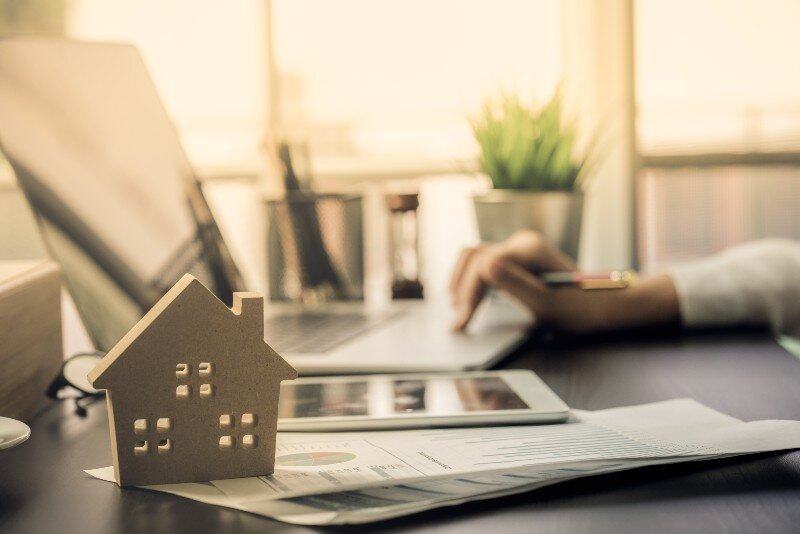 A person reviewing some documents and doing some research online about housing markets.