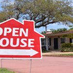 Open house real estate sign in yard, with house in background.