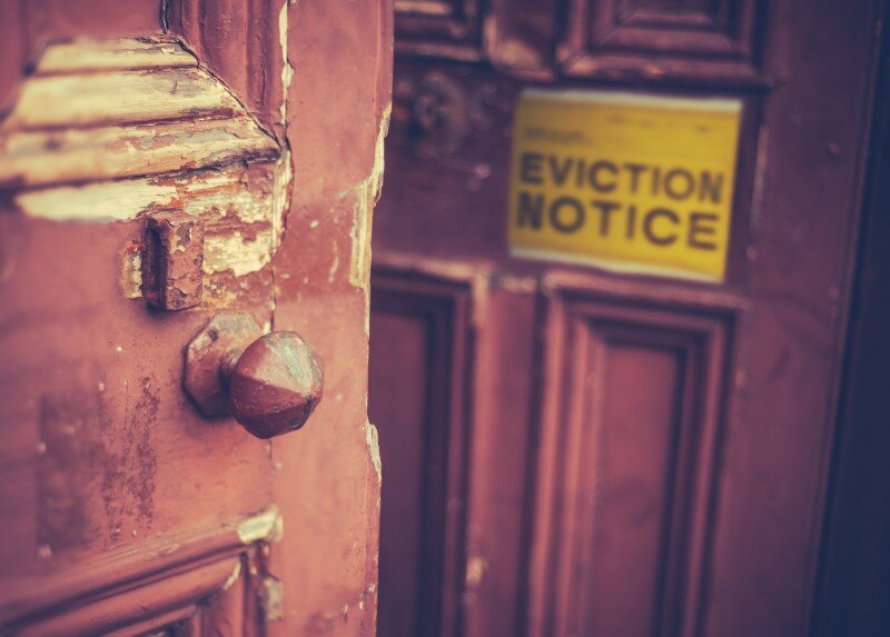 A deteriorated wooden door with an eviction notice. 