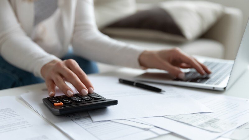 A woman calculates closing costs on a house sale.