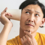 Man listening to a cup on a string while thinking about 5 Misconceptions People Have About Professional Home Buyers in Greenville NC