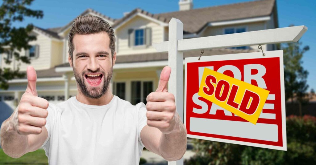 A happy homeowner with a sold sign in front of their house