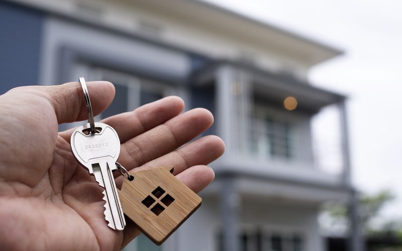 Hand holding key in front of house