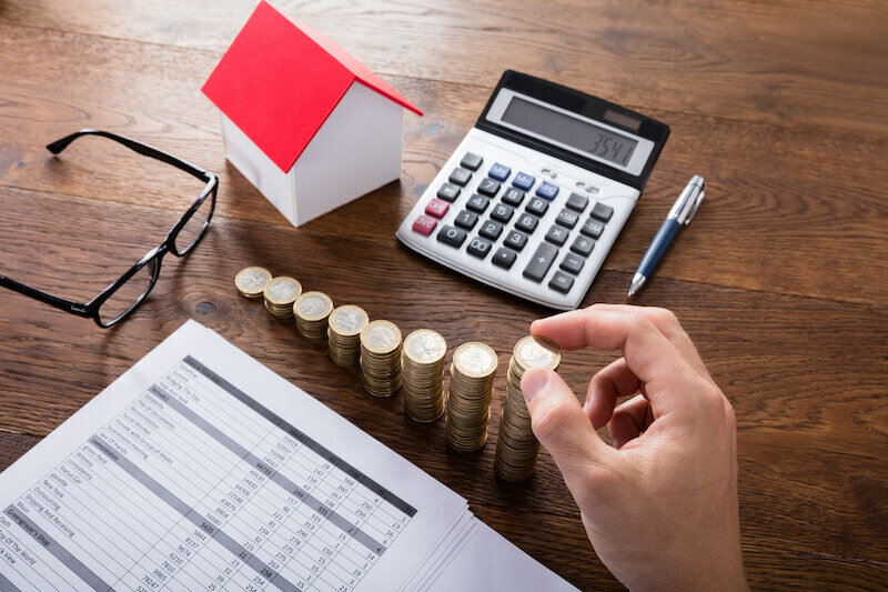 Person Liquidating hid assets 
 - Stacking Coins Near House On Wooden Desk