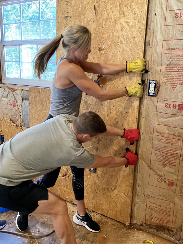 Man and Woman pulling plywood off a wall