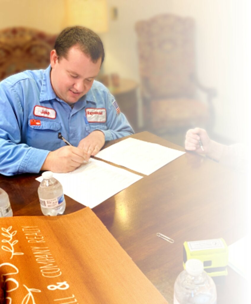 Photograph of a man signing paperwork in an office