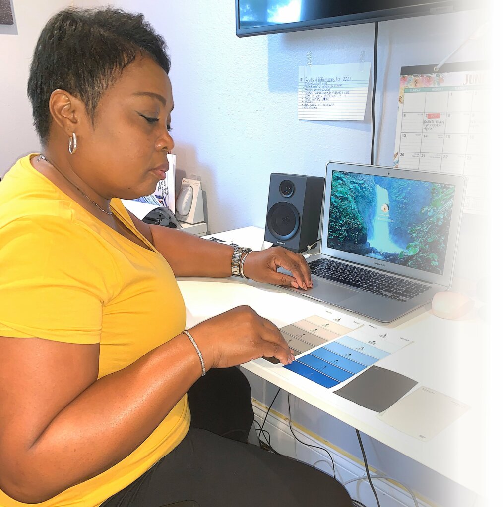 black female sitting at desk looking at interior color paint chips