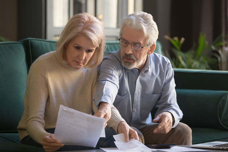 An elderly couple looking at a paper and reading all the North Carolina property taxes they need to know before selling