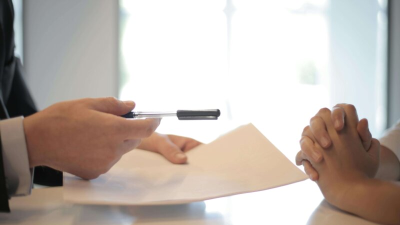 Two people sitting at a table with papers and pen. A cover in How to Spot a Good Real-Estate Investment and Buy a House Quickly in Wilmington blog post.