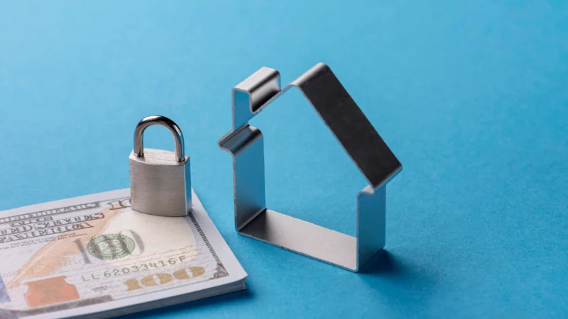 A lock on top of a bill beside a house.