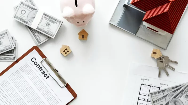 Contract, a miniature house and some coins on the table