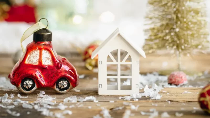 a small red car next to a small white house