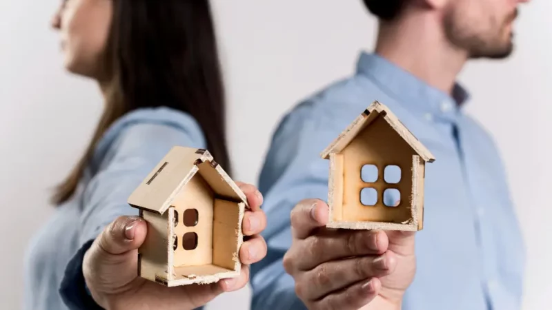 People holding 2 houses made of cardboard