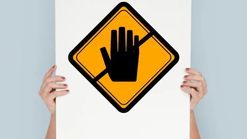 a woman holding up a sign with a hand on it