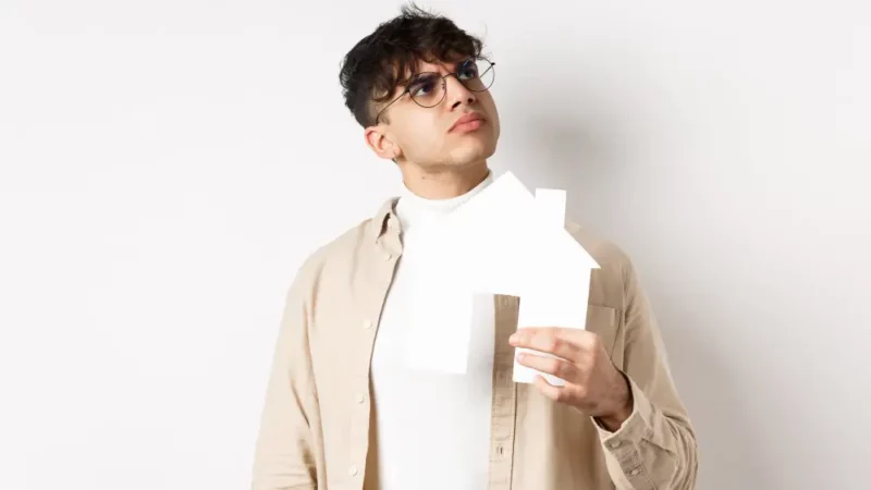 a man holding a piece of paper in his hands in the shape of a house