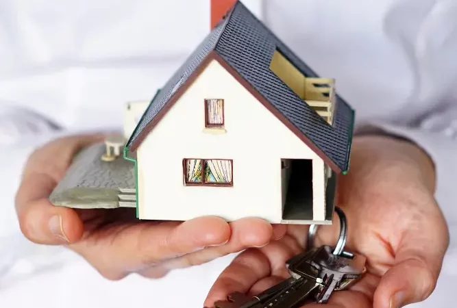 man holding a miniature house and key