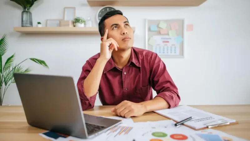 Man thinking with a laptop in front of him