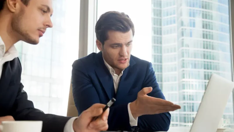 Two men having a discussion in front of a laptop