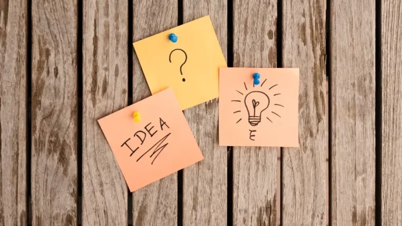 The word idea, question mark, and a light bulb on a post-it note.
