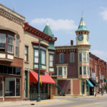 Historic downtown buildings with colorful storefronts and a clock tower in New Berlin.