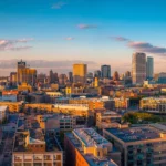 Aerial view of downtown Milwaukee skyline at sunset with modern buildings and Lake Michigan in the background.