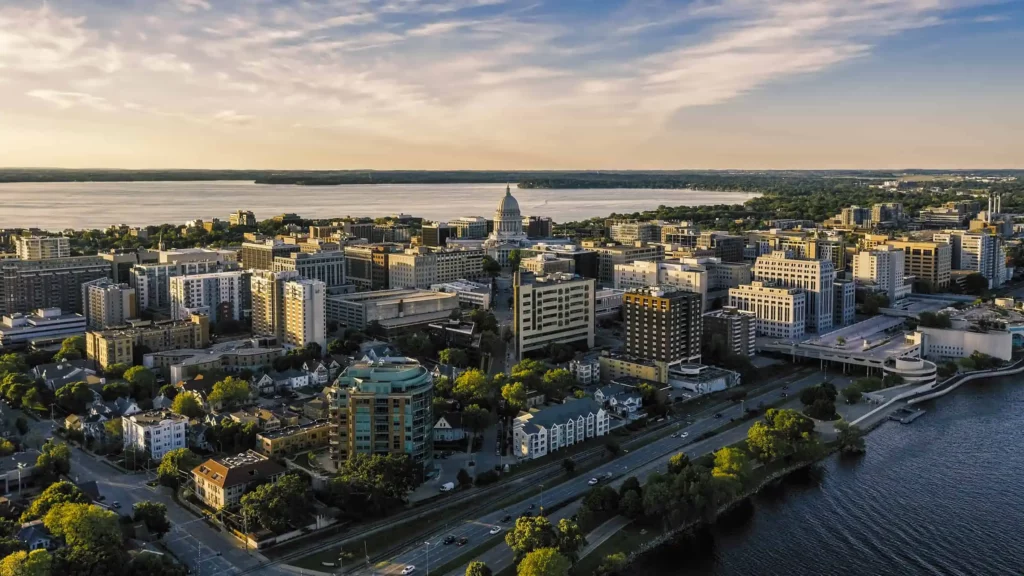 Aerial view of downtown Madison, Wisconsin, with the State Capitol and surrounding buildings at sunset.