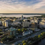 Aerial view of downtown Madison, Wisconsin, with the State Capitol and surrounding buildings at sunset.