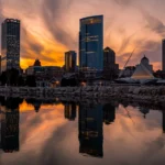 Milwaukee skyline at sunset with tall buildings reflecting on Lake Michigan.