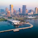 Aerial view of downtown Milwaukee skyline at sunrise over Lake Michigan.