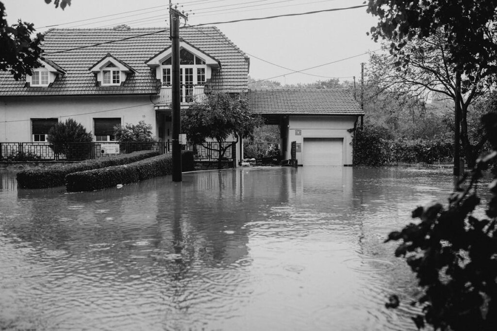 A black and white picture of a house that is flooded